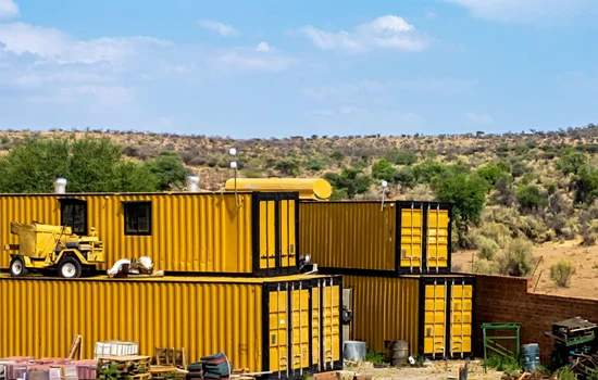 Stacked yellow shipping containers utilized as functional site offices or secure equipment storage at a project location.